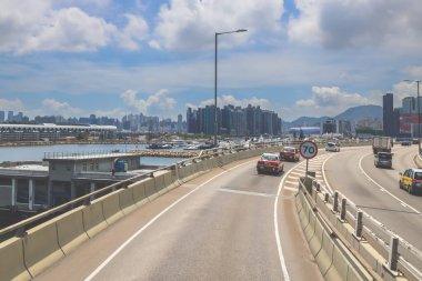 Kavisli bir karayolu, araçlar ve manzaralı bir şehir silueti içeren şehir yolu.