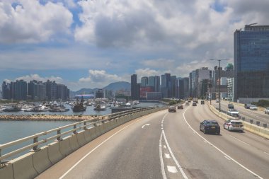 Kavisli bir karayolu, araçlar ve manzaralı bir şehir silueti içeren şehir yolu.