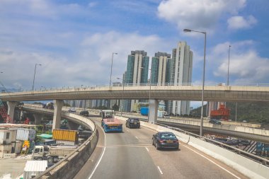 Yükseltilmiş bir otoyolu, hareket halindeki bir aracı gösteren hareketli bir şehir manzarası
