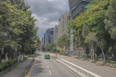 Şehir yolu modern binalarla, yemyeşil ağaçlarla dolu.