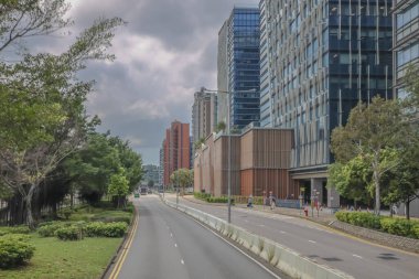 Şehir yolu modern binalarla, yemyeşil ağaçlarla dolu.