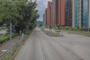 Şehir yolu modern binalarla, yemyeşil ağaçlarla dolu.