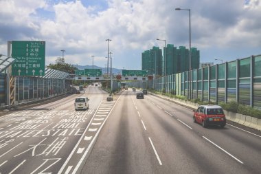 Modern bir otoyolda bulutlu gökyüzünün altında seyahat eden arabalar vardır.,