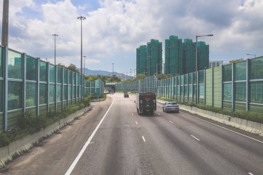 Modern bir otoyolda bulutlu gökyüzünün altında seyahat eden arabalar vardır.,