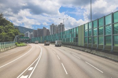 Modern bir otoyolda bulutlu gökyüzünün altında seyahat eden arabalar vardır.,