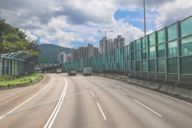 Modern bir otoyolda bulutlu gökyüzünün altında seyahat eden arabalar vardır.,