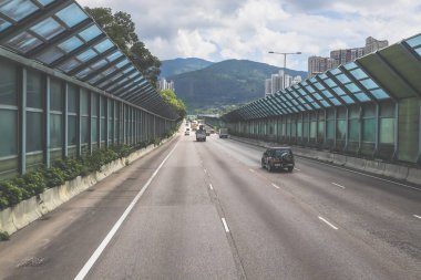 Modern bir otoyolda bulutlu gökyüzünün altında seyahat eden arabalar vardır.,