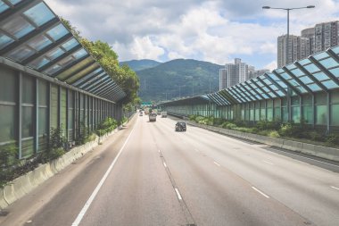 Modern bir otoyolda bulutlu gökyüzünün altında seyahat eden arabalar vardır.,