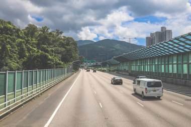 Modern bir otoyolda bulutlu gökyüzünün altında seyahat eden arabalar vardır.,