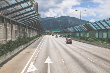 Modern bir otoyolda bulutlu gökyüzünün altında seyahat eden arabalar vardır.,