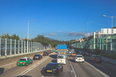 açık mavi gökyüzünün altındaki ağaçların ve binaların arka planı. Canlı bir şehirde güneşli bir günde, şehir içi gidip gelen yaşam tarzını yakalar..