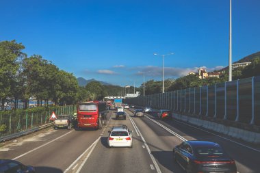 açık mavi gökyüzünün altındaki ağaçların ve binaların arka planı. Canlı bir şehirde güneşli bir günde, şehir içi gidip gelen yaşam tarzını yakalar..