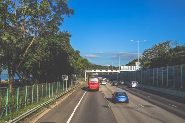açık mavi gökyüzünün altındaki ağaçların ve binaların arka planı. Canlı bir şehirde güneşli bir günde, şehir içi gidip gelen yaşam tarzını yakalar..