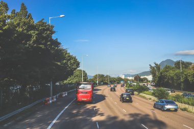 açık mavi gökyüzünün altındaki ağaçların ve binaların arka planı. Canlı bir şehirde güneşli bir günde, şehir içi gidip gelen yaşam tarzını yakalar..