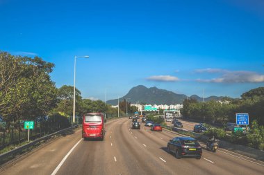 açık mavi gökyüzünün altındaki ağaçların ve binaların arka planı. Canlı bir şehirde güneşli bir günde, şehir içi gidip gelen yaşam tarzını yakalar..