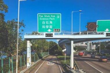 Çevresi yeşilliklerle çevrili, bakımlı bir otoyol boyunca giden araçlar.