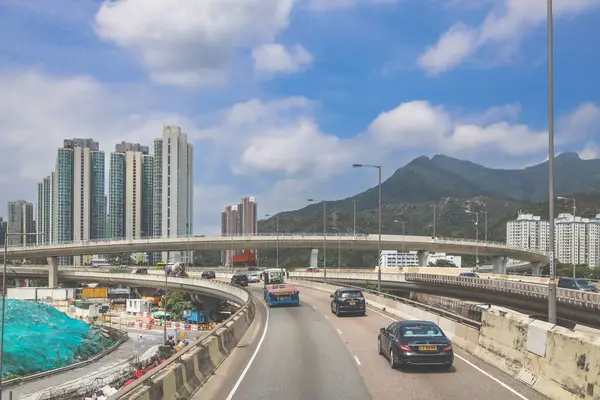 Yükseltilmiş bir otoyolu, hareket halindeki bir aracı gösteren hareketli bir şehir manzarası