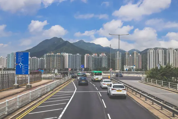 Şehir kavşağı trafiği, şehir silüeti ve güneşli bir havanın altındaki dağlar