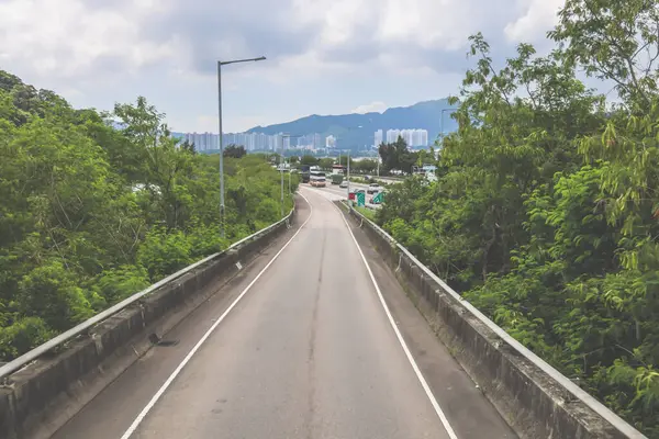 Çevresi yeşilliklerle çevrili, bakımlı bir otoyol boyunca giden araçlar.