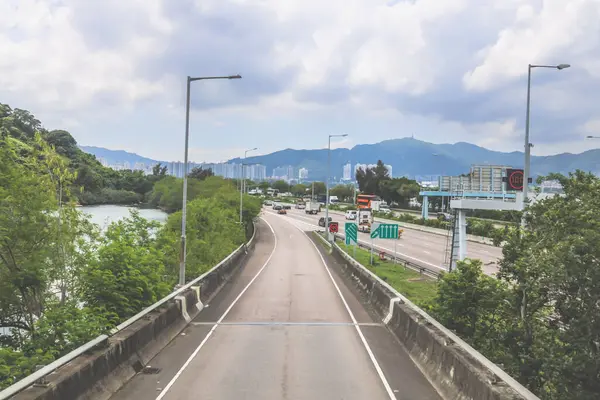 Çevresi yeşilliklerle çevrili, bakımlı bir otoyol boyunca giden araçlar.
