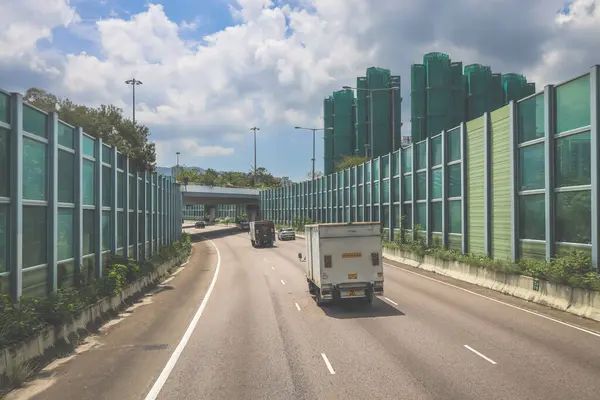 Modern bir otoyolda bulutlu gökyüzünün altında seyahat eden arabalar vardır.,