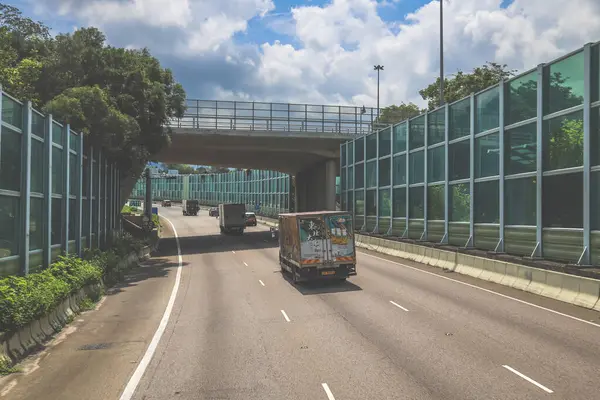 Modern bir otoyolda bulutlu gökyüzünün altında seyahat eden arabalar vardır.,