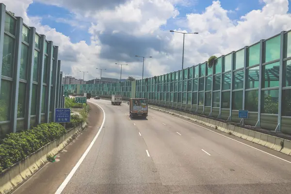 Modern bir otoyolda bulutlu gökyüzünün altında seyahat eden arabalar vardır.,