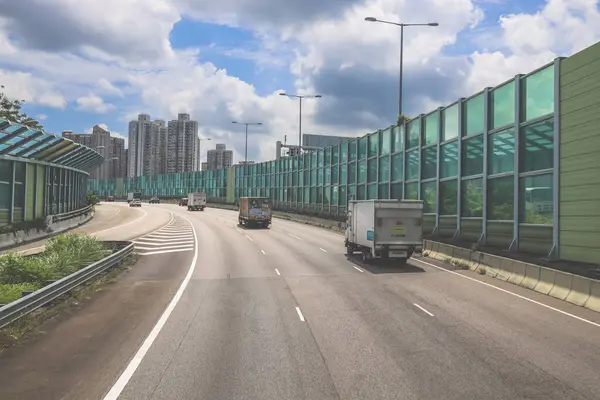 Modern bir otoyolda bulutlu gökyüzünün altında seyahat eden arabalar vardır.,