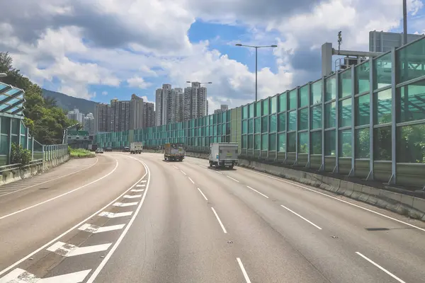 Modern bir otoyolda bulutlu gökyüzünün altında seyahat eden arabalar vardır.,