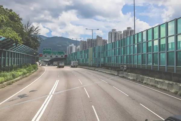 Modern bir otoyolda bulutlu gökyüzünün altında seyahat eden arabalar vardır.,