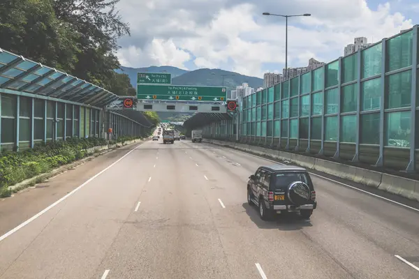 Modern bir otoyolda bulutlu gökyüzünün altında seyahat eden arabalar vardır.,