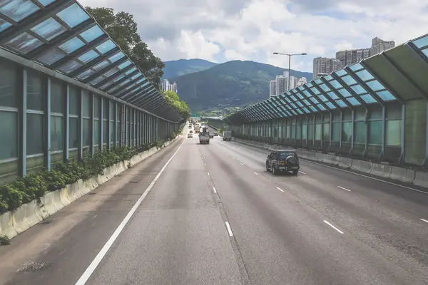 Modern bir otoyolda bulutlu gökyüzünün altında seyahat eden arabalar vardır.,