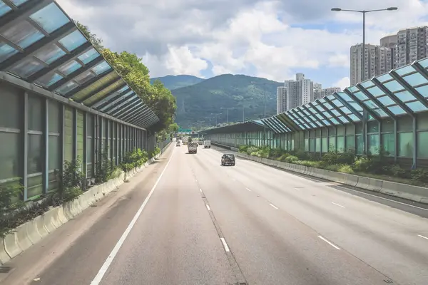 Modern bir otoyolda bulutlu gökyüzünün altında seyahat eden arabalar vardır.,