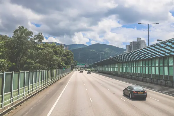 Modern bir otoyolda bulutlu gökyüzünün altında seyahat eden arabalar vardır.,