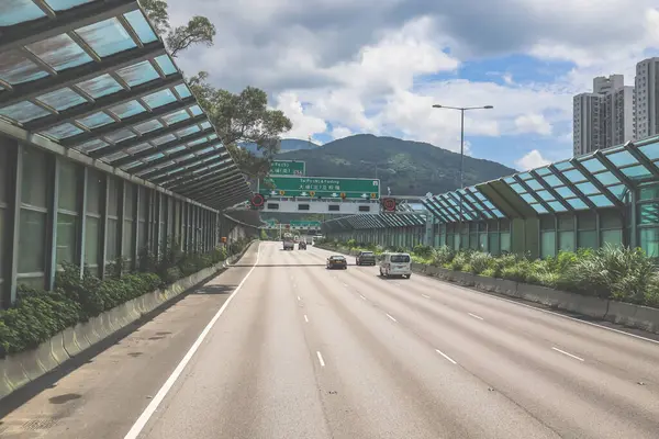 Modern bir otoyolda bulutlu gökyüzünün altında seyahat eden arabalar vardır.,