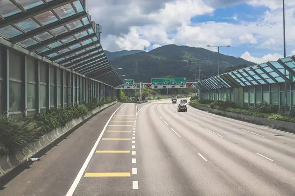 Modern bir otoyolda bulutlu gökyüzünün altında seyahat eden arabalar vardır.,