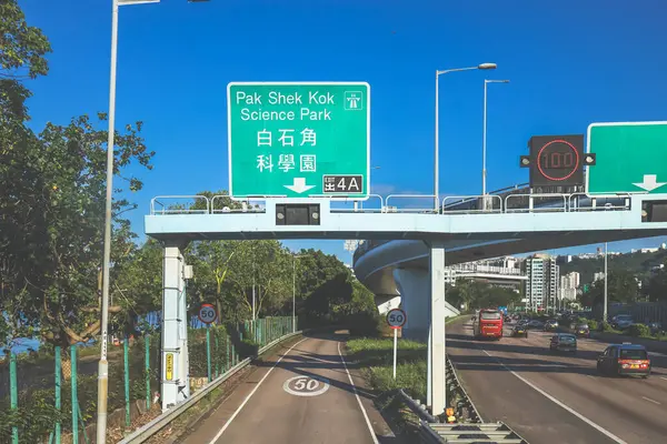 Çevresi yeşilliklerle çevrili, bakımlı bir otoyol boyunca giden araçlar.