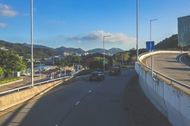 Şehir kavşağı trafiği, şehir silüeti ve güneşli bir havanın altındaki dağlar