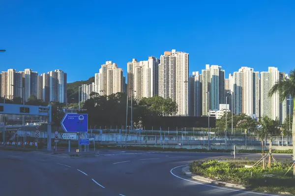 Güneşli şehir manzarasında yükseltilmiş bir yol yükselişte bir apartmana çıkıyor.