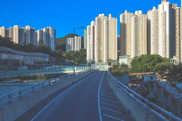 Güneşli şehir manzarasında yükseltilmiş bir yol yükselişte bir apartmana çıkıyor.