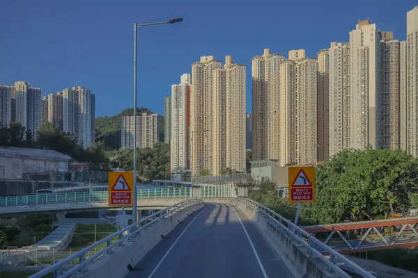 Güneşli şehir manzarasında yükseltilmiş bir yol yükselişte bir apartmana çıkıyor.
