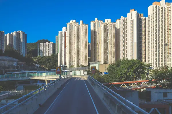 Güneşli şehir manzarasında yükseltilmiş bir yol yükselişte bir apartmana çıkıyor.