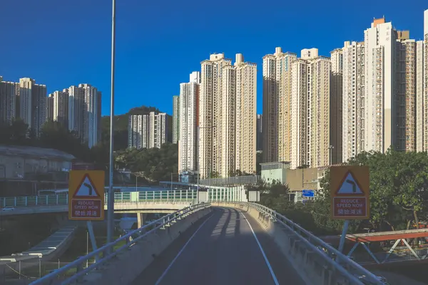 Güneşli şehir manzarasında yükseltilmiş bir yol yükselişte bir apartmana çıkıyor.