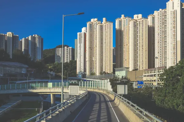 Güneşli şehir manzarasında yükseltilmiş bir yol yükselişte bir apartmana çıkıyor.