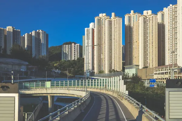 Güneşli şehir manzarasında yükseltilmiş bir yol yükselişte bir apartmana çıkıyor.