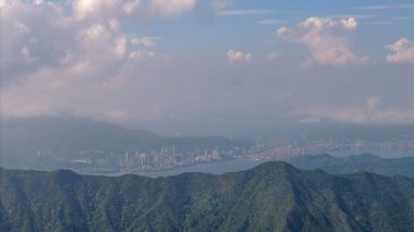 Sahil kenti olan ön plandaki dağlar ve uzaktaki bulutlu gökyüzü..