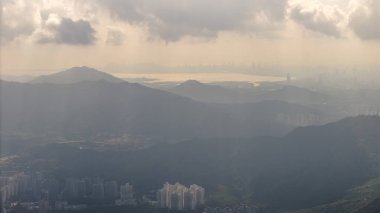 Sahil kenti olan ön plandaki dağlar ve uzaktaki bulutlu gökyüzü..