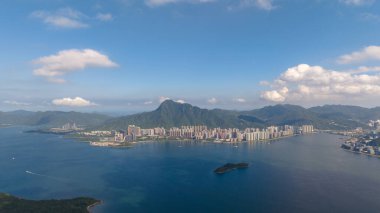 Verimli yeşil tepeler tarafından çerçevelenmiş bir kıyı şehri manzarası