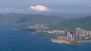 Yeşil tepenin arasına kurulmuş modern bir sahil kenti sergileniyor.