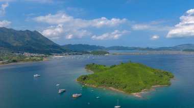 Etrafı yemyeşil dağlarla çevrili sakin bir sahil şeridi sergileniyor.